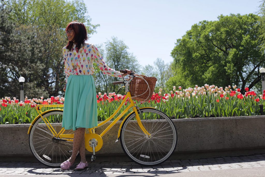 girl standing with bike in front of tulips
